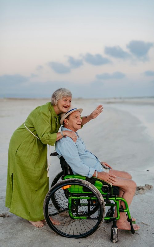 Senior man on wheelchair enjoying together time with his wife at sea.